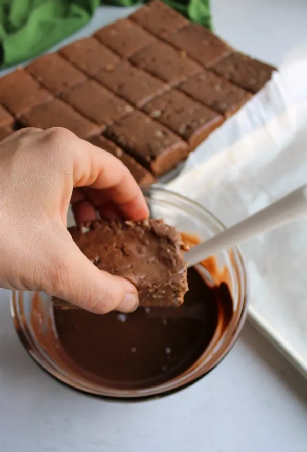 dipping chocolate peanut butter rice krispie treats into melted Chocolate.