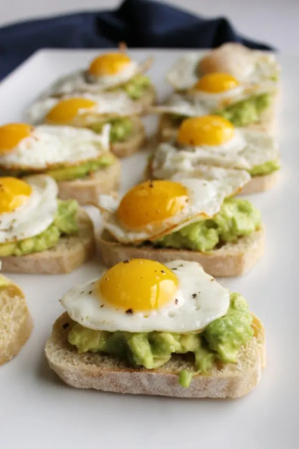 baguette slices topped with avocado and fried quail eggs