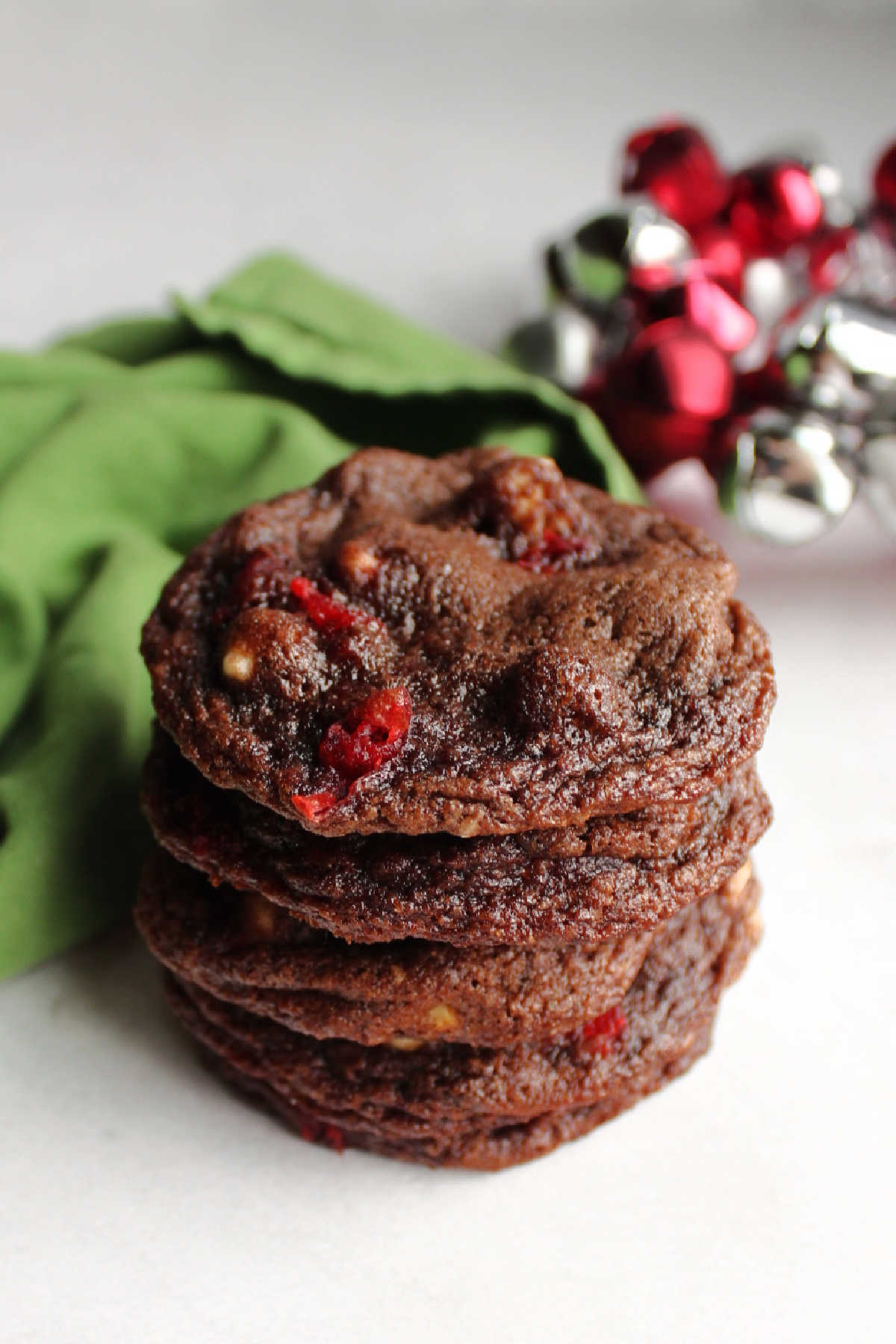 Stack of chocolate cherry chip cookies with festive bells in the background.