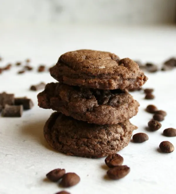 close stack of mocha chocolate chunk cookies with chunks of chocolate and coffee beans scattered around.