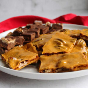 golden pecan brittle on plate with squares of fudge.