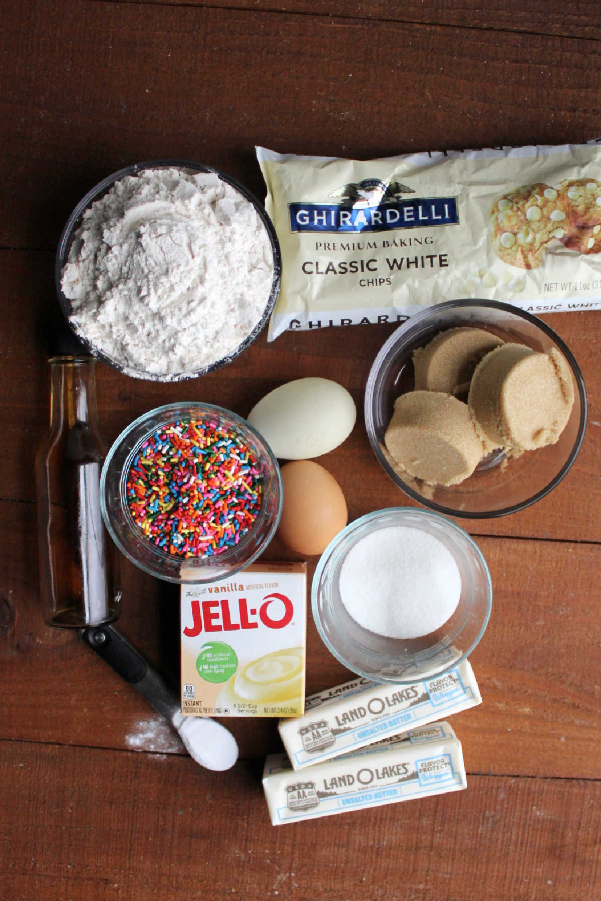 Ingredients for funfetti birthday cookies including butter, sugar, brown sugar, eggs, pudding mix, baking soda, flour, vanilla, sprinkles, and white chocolate chips.