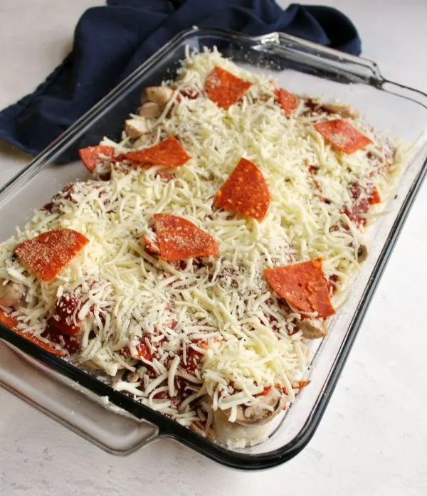 pan of bubble up pizza covered with shredded mozzarella and pepperoni ready to be baked.