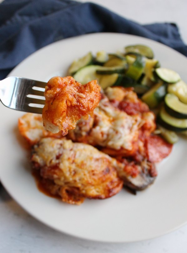 fork of sauce covered biscuit from bubble up pizza by dinner plate with zucchini