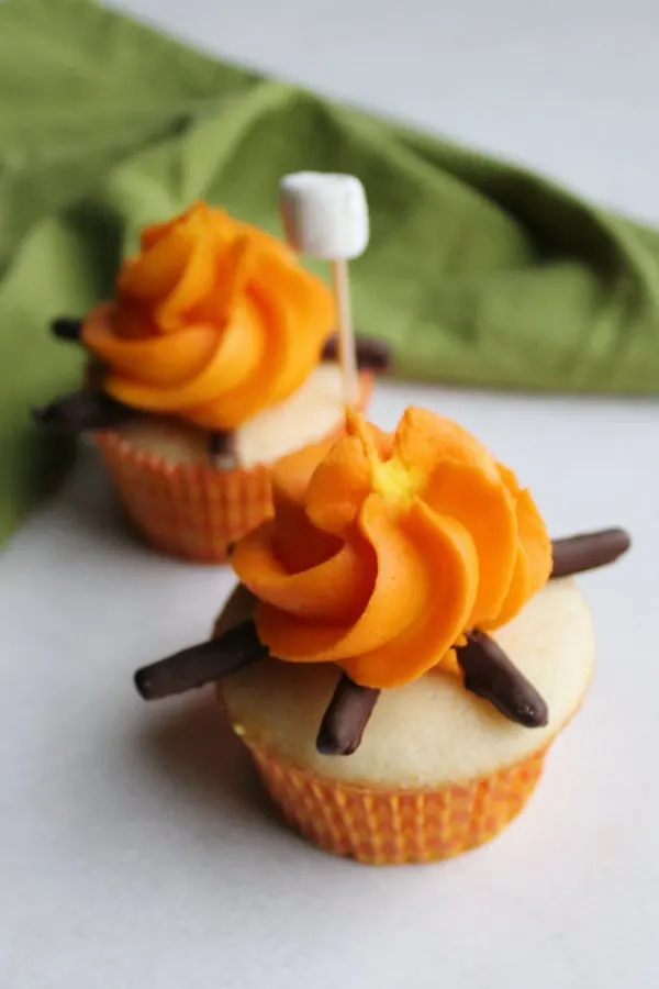 two campfire cupcakes with a mini marshmallow on a stick ready to be roasted