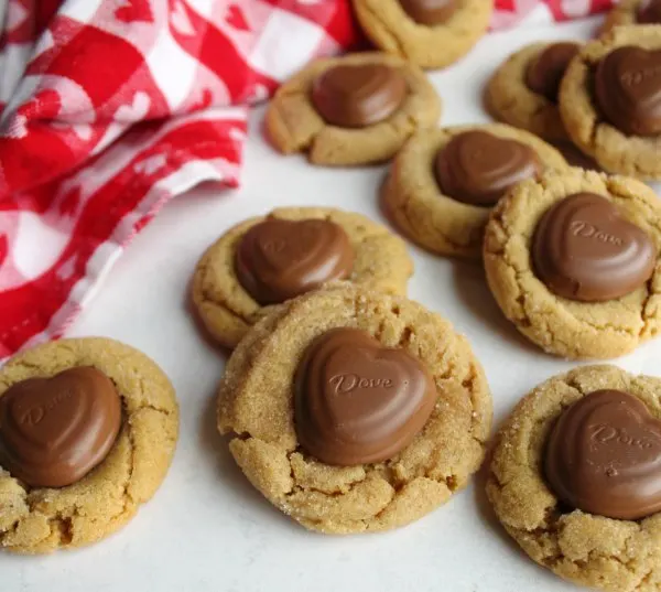 pile of peanut butter blossom cookies with chocolate heart centers.