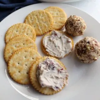 plate with 2 mini cranberry cheese balls, butter crackers and some cheese ball spread on crackers.