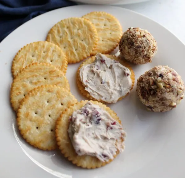 plate with 2 mini cranberry cheese balls, butter crackers and some cheese ball spread on crackers.
