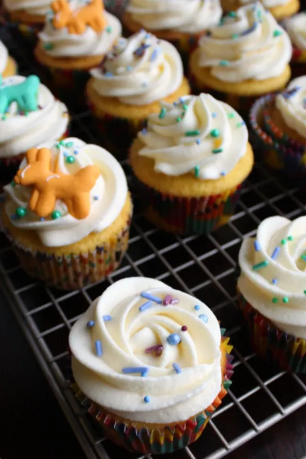 Swirls of russian buttercream piped onto cupcakes and topped with colorful sprinkles.