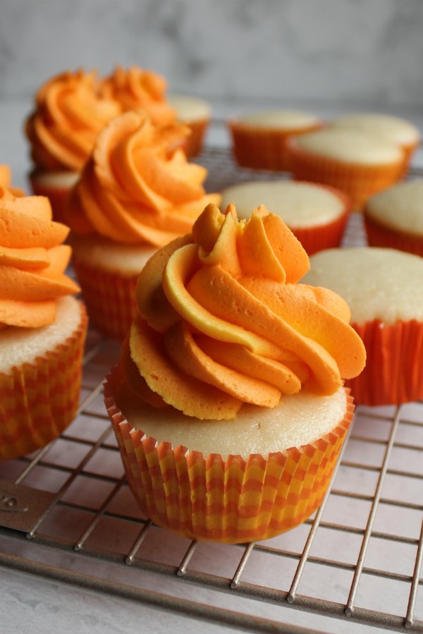 orange and yellow swirled frosting piped on top of semi-homemade white cupcakes