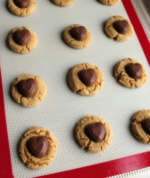 warm peanut butter blossoms with milk chocolate heart centers on baking tray