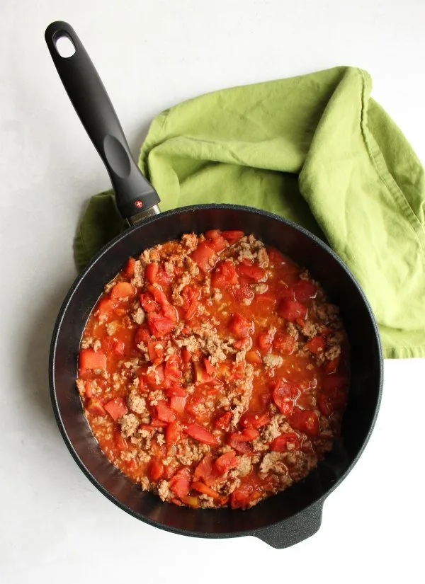 saute pan filled with tomato and ground beef mixture for casserole.
