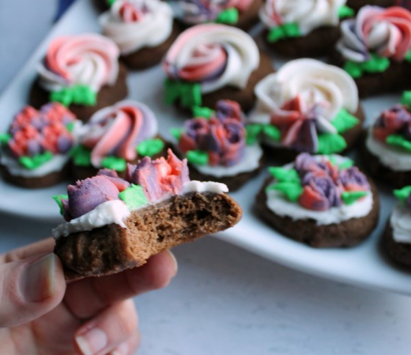 bite missing from chocolate cookie with buttercream flowers on top.