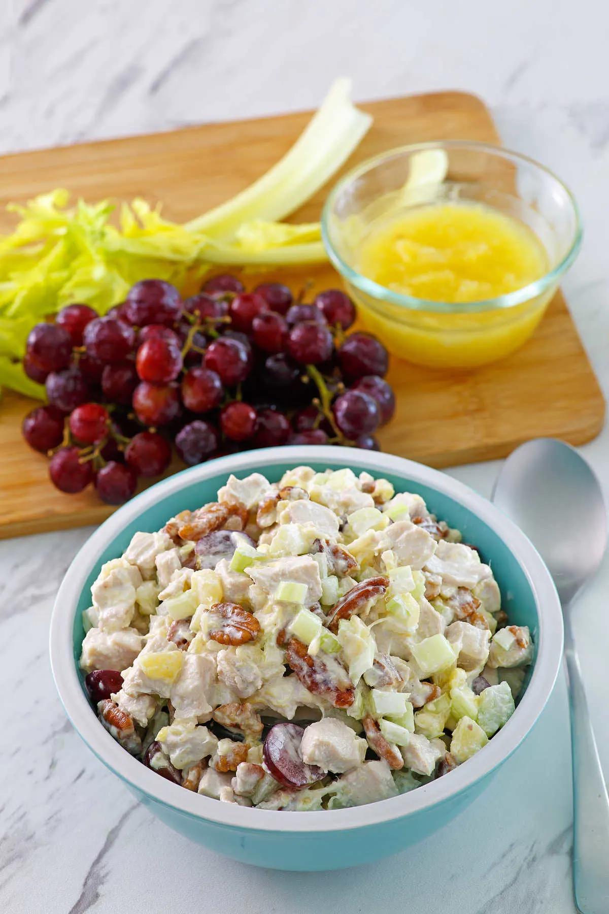 bowl of chicken salad with grapes, celery and pineapple in background.