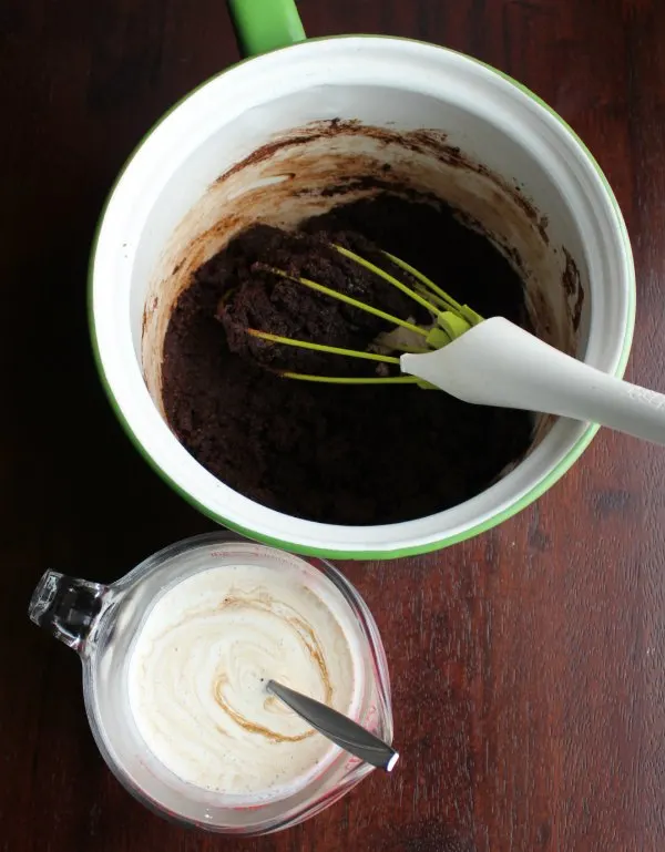 butter and cocoa mixture in saucepan and measuring cup with cream and sour cream mix