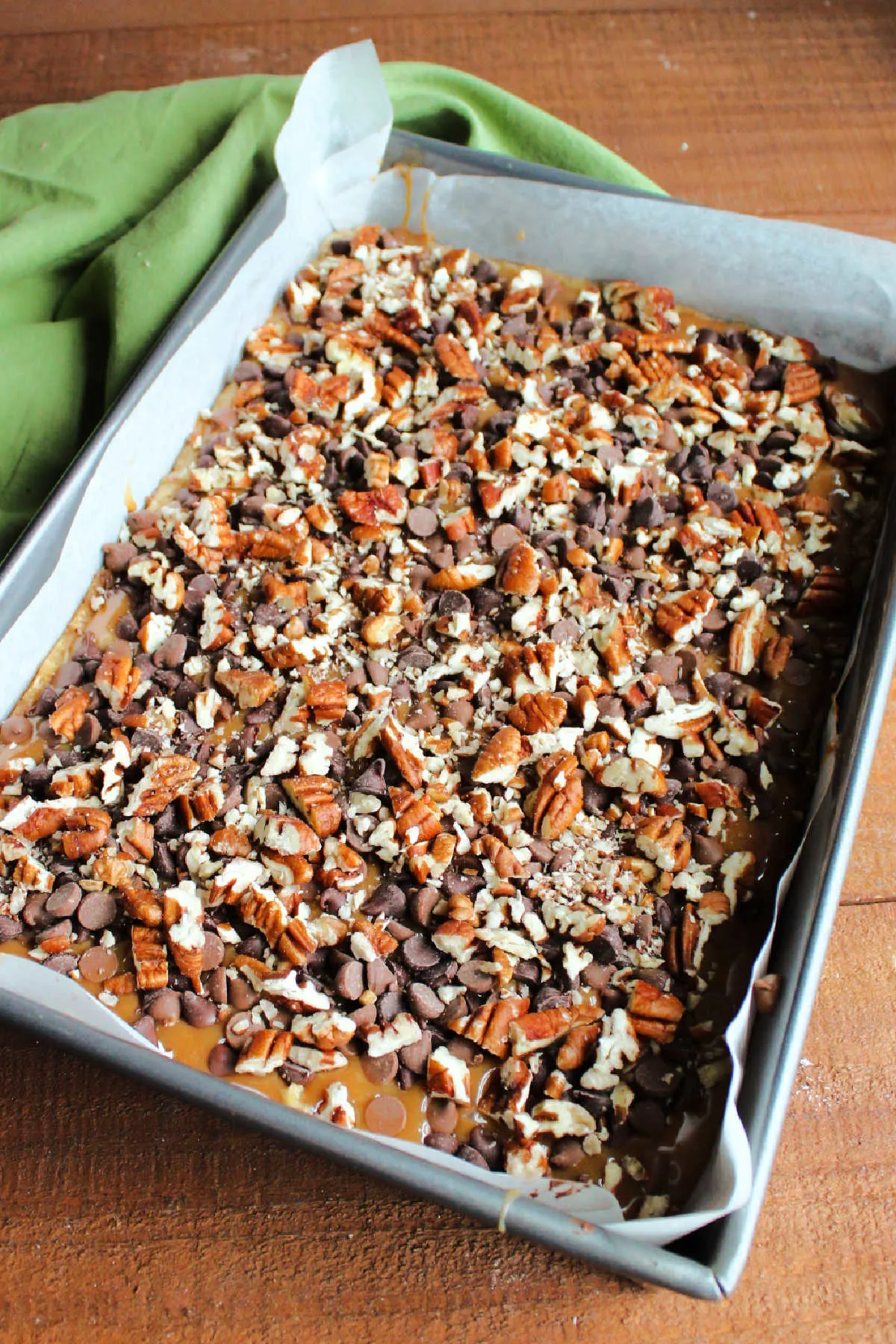 Bottom oatmeal cookie layer topped with melted caramel, chocolate chips and chopped pecans.
