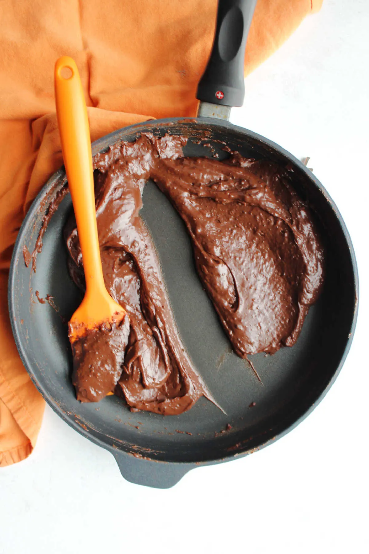 Cooked chocolate brigadeiro filling in skillet showing how it holds its shape after a spatula has run through it. 