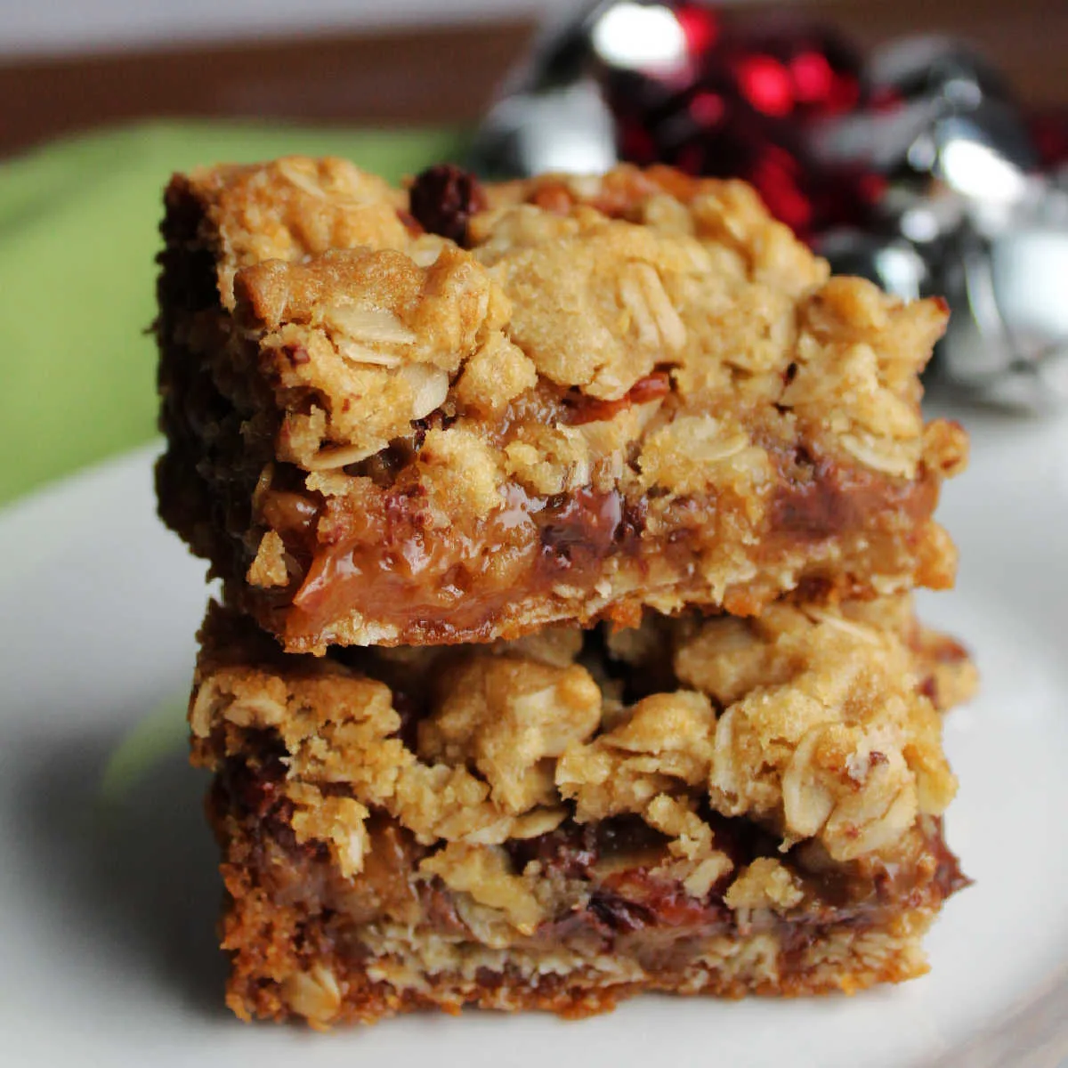 Stack of cookie bars with oatmeal crust and gooey caramel, chocolate and pecan centers.