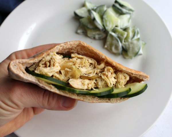 close up of inside of pita pocket stuffed with shredded chicken and cucumber slices