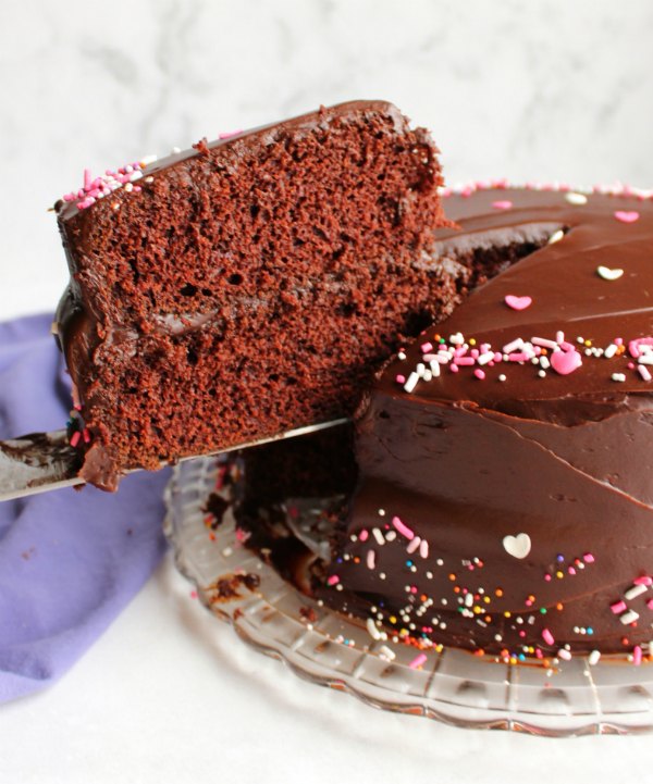 lifting out slice of devilishly good chocolate layer cake with shiny fudge frosting