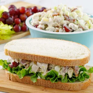 Pineapple chicken salad sandwich with lettuce ready to eat with bowl of more fruited chicken salad behind it.