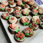 Platter of round chocolate sour cream cookies topped with buttercream rosettes and flowers.