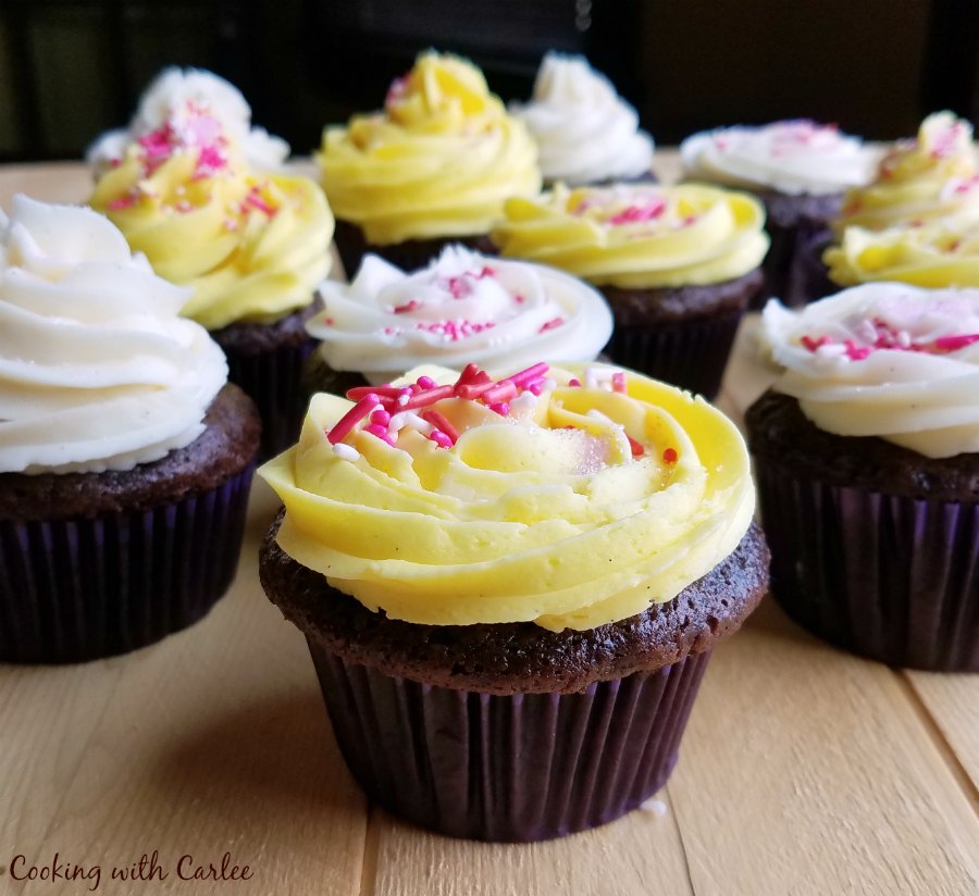 group of chocolate banana cupcakes with white and yellow frosting and pink sprinkles