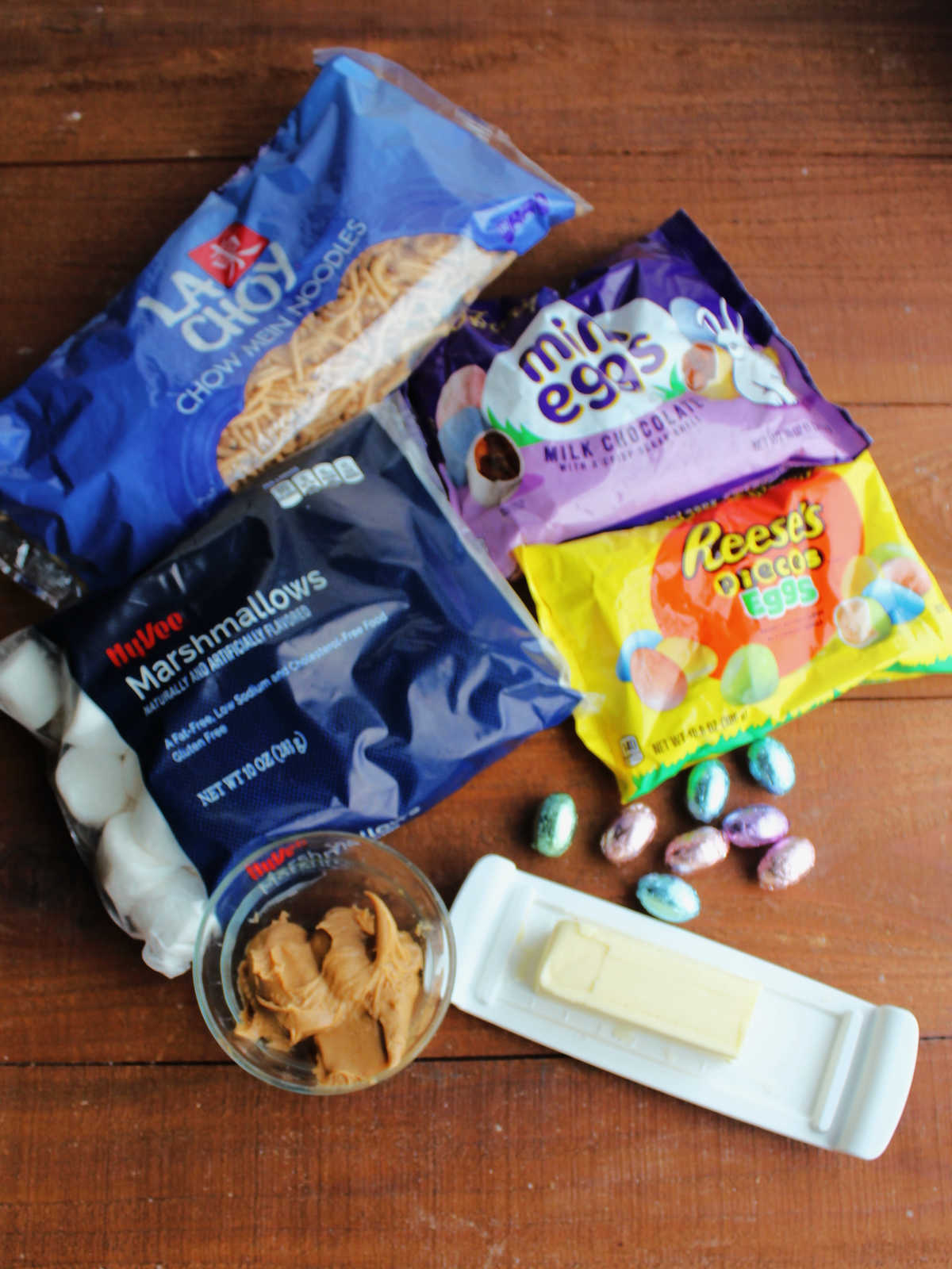 Ingredients including crunchy chow mein noodles, marshmallows, butter, peanut butter and candy eggs ready to be made into edible nests.