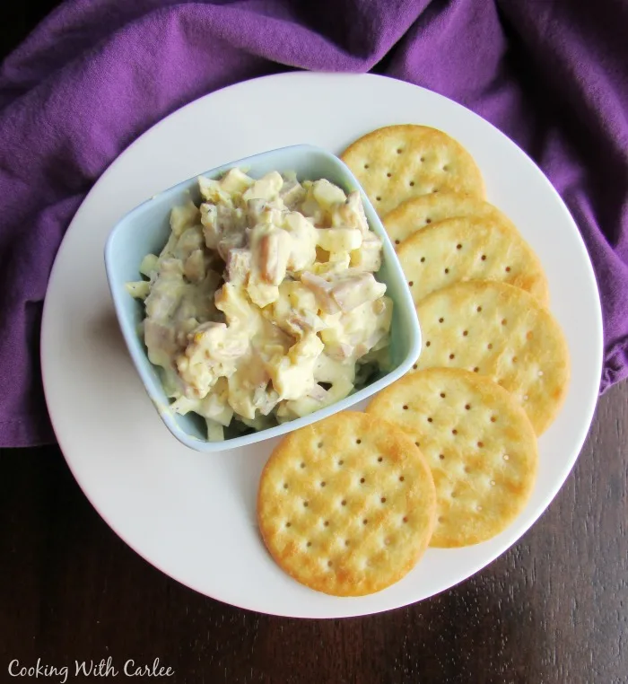Small bowl of deviled ham and egg salad on plate with crackers ready to eat.