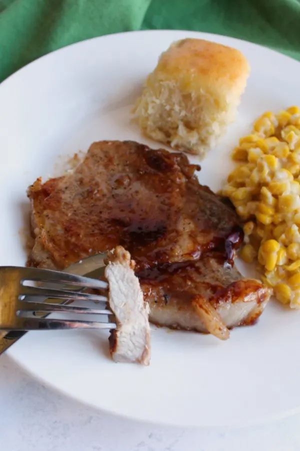 fork with tender piece of pork chop on it showing white center vs. dark sticky glaze on the outside