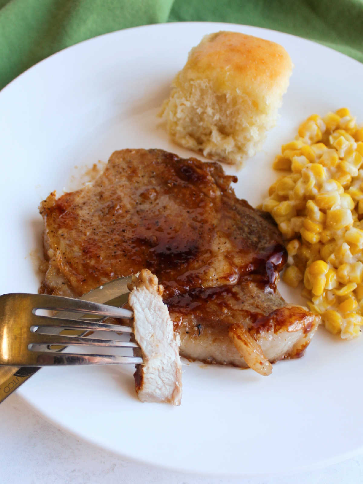 fork with tender piece of pork chop on it showing white center vs. dark sticky glaze on the outside.