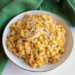 bowl of creamy parmesan corn with shredded cheese on top ready to be served.