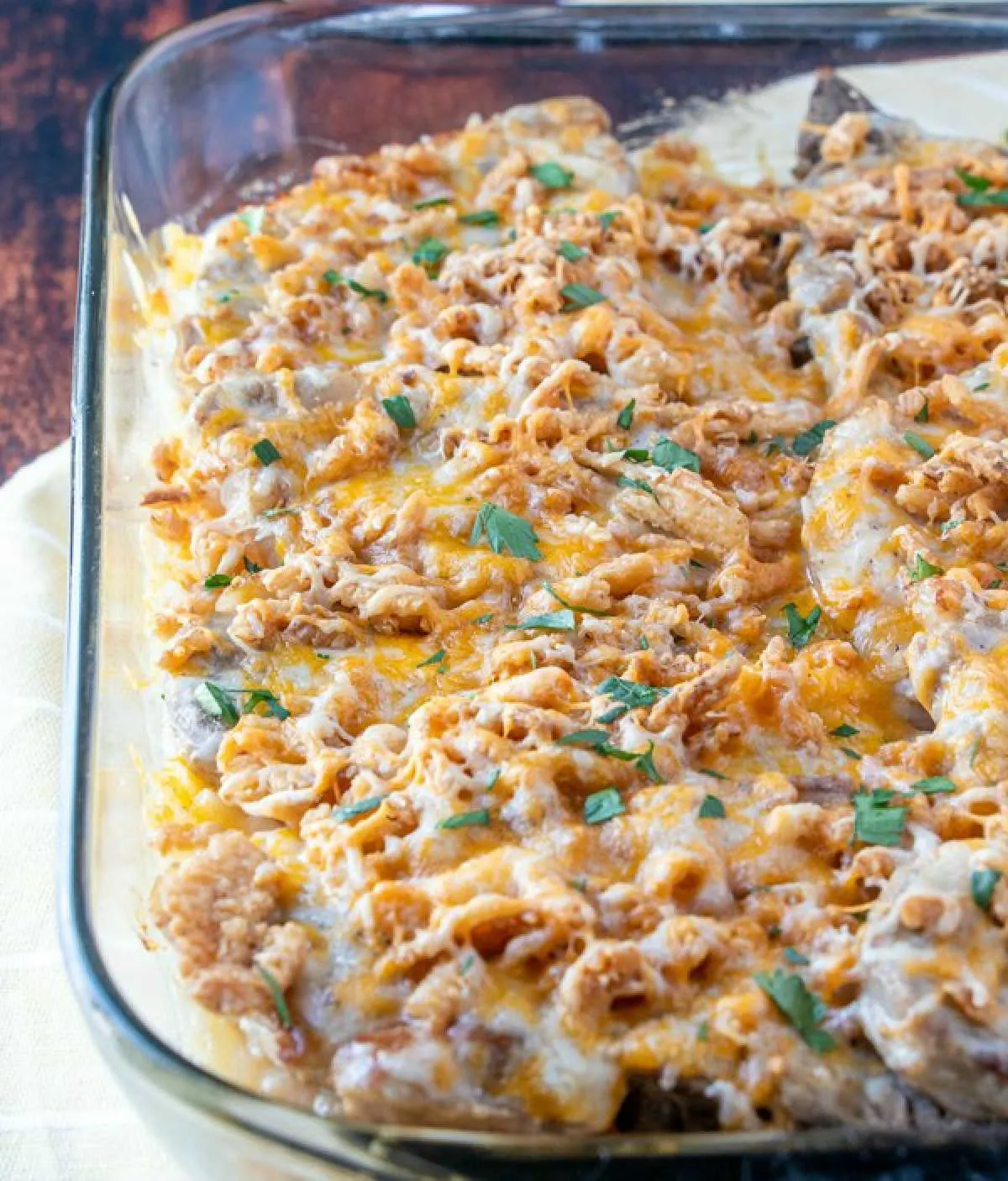 Casserole dish loaded with cheesy pork chop and potato bake topped with french fried onions and fresh herbs. 