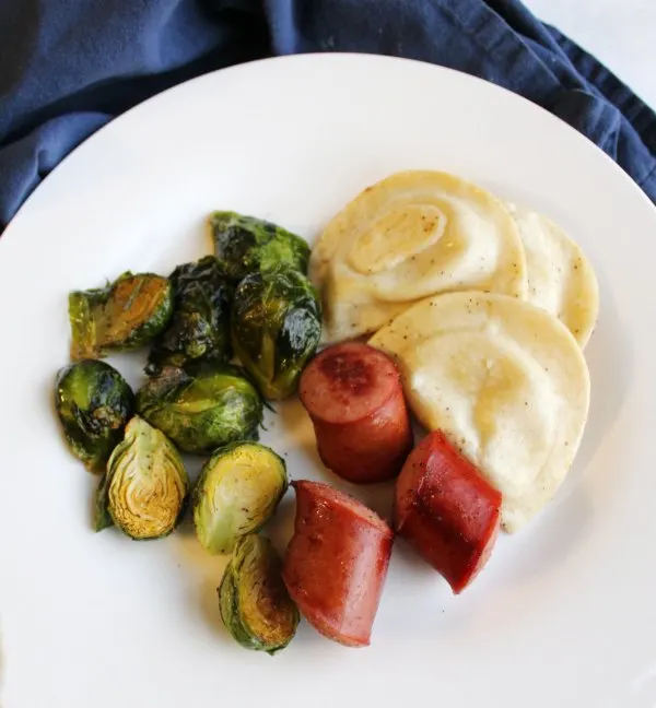 dinner plate of sheet pan meal with sausage, pierogies and brussels sprouts