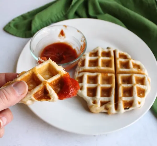 piece of pizza waffle dipped in marinara ready to eat.
