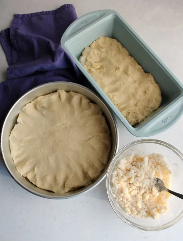 pans of placek dough next to bowl of crumb topping.