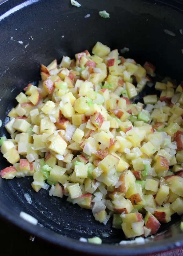 small cubes of potato, chopped celery and onion being cooked in dutch oven.