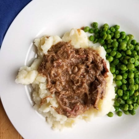 Balsamic Braised Pork Shoulder 4 Shredded balsamic braised pork served on a bed of mashed potatoes with green peas on the side.