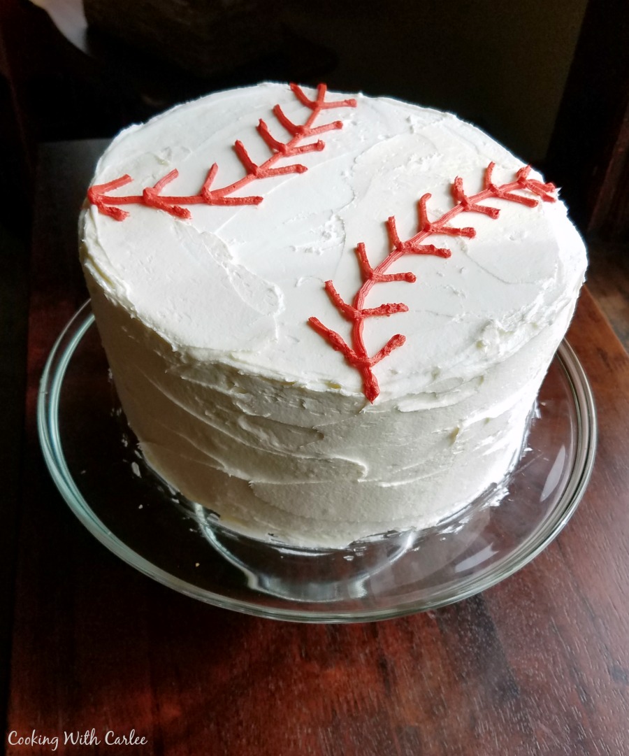 round layer cake iced with white chocolate buttercream and red laces to look like a baseball.