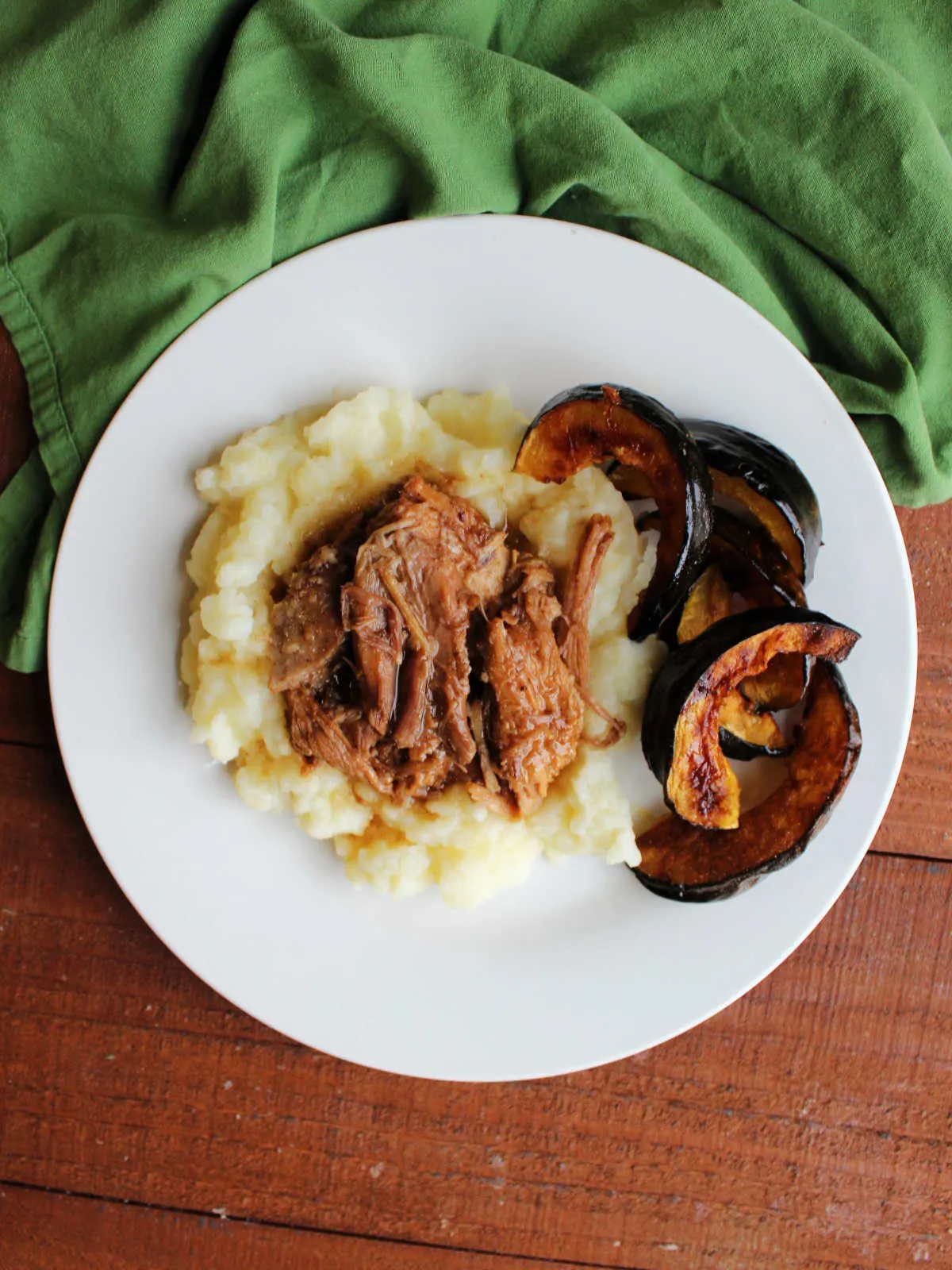 Dinner plate with roasted acorn squash, mashed potatoes and tender pork served in balsamic gravy.