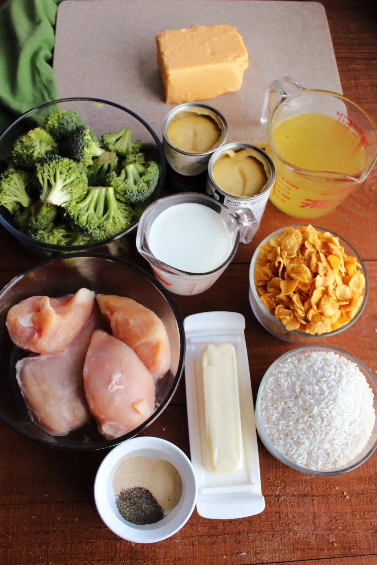Ingredients including chicken, broccoli, velveeta, rice, cream of chicken soup, butter, milk, chicken broth, and seasonings ready to be made into casserole.