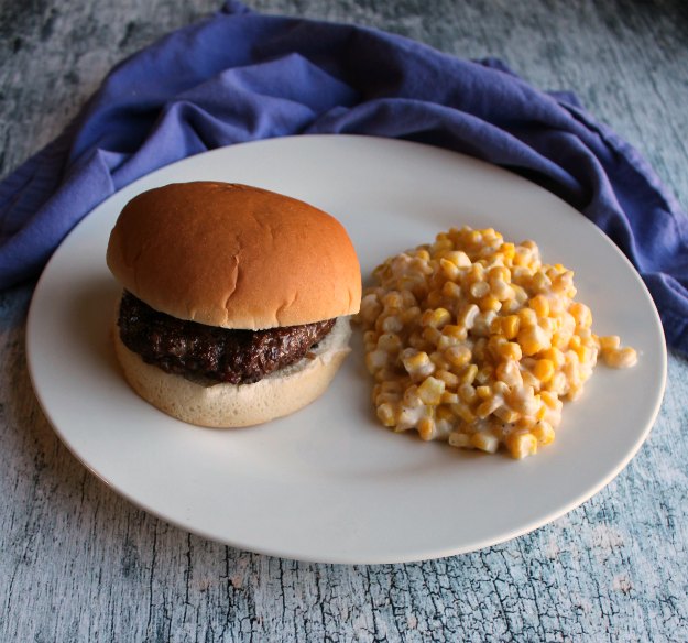 hamburger and creamy corn on plate.