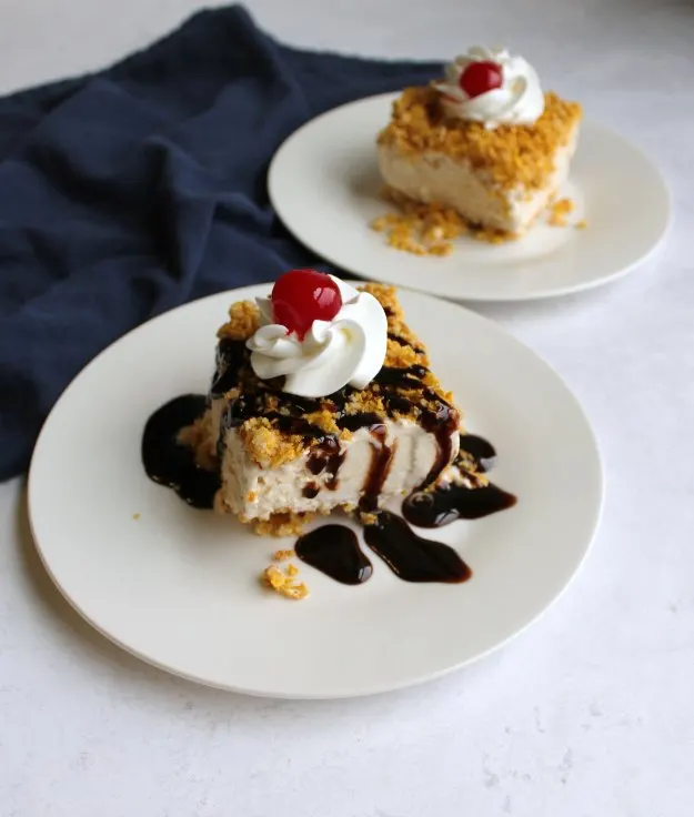 two plates of fried ice cream bars, one with chocolate syrup drizzle, both with whipped cream and cherry