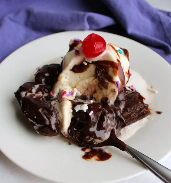brownie topped with ice cream, hot fudge and a cherry