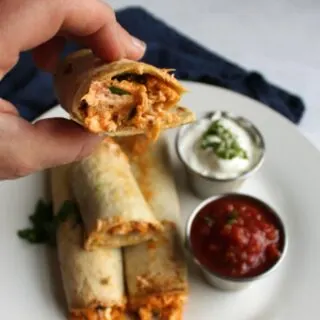 hand holding creamy taquito with shredded chicken