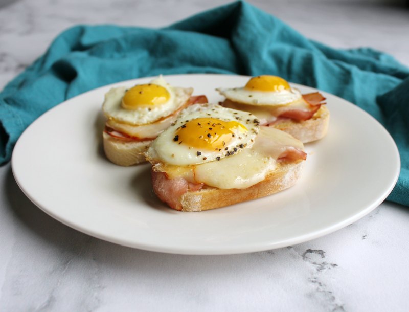 looking across a plate of ham and cheese crostini with fried quail eggs on top.