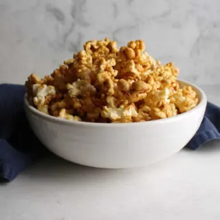 white bowl filled with cracker jack style crunchy caramel corn with lots of peanuts.