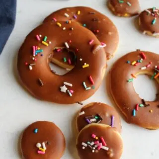 donut shaped sugar cookies with setting fudge icing and sprinkles on top
