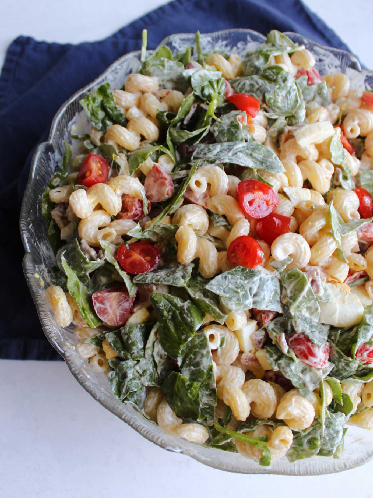 Close up of a bowl of creamy blt pasta salad with spinach, avocado, and eggs.