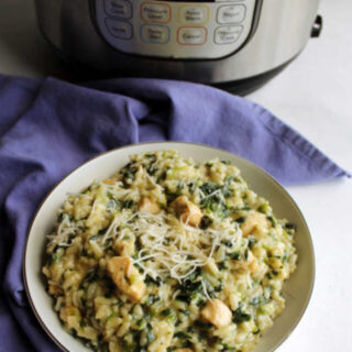 bowl of creamy risotto with chicken and spinach topped with Parmesan cheese in front of instant pot